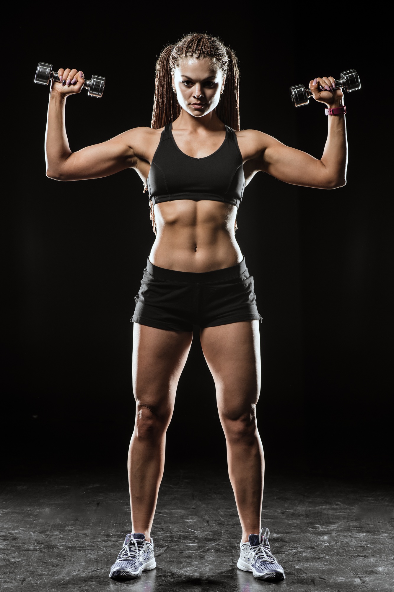 Fitness girl with dumbbells on a dark background isolated