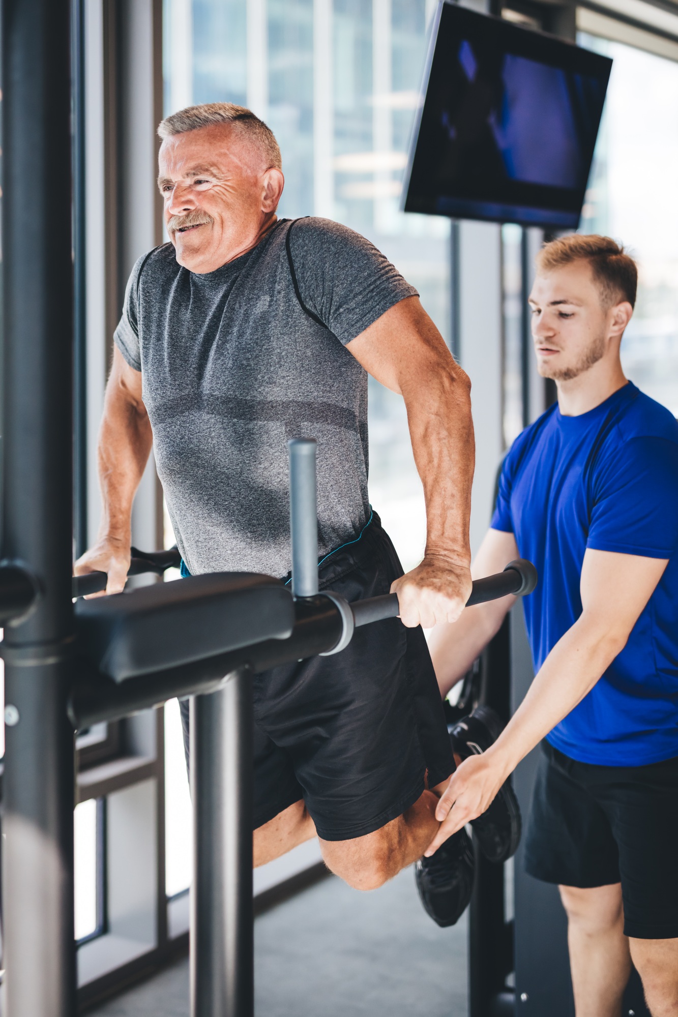 Gym instructor helping senior man at the gym.